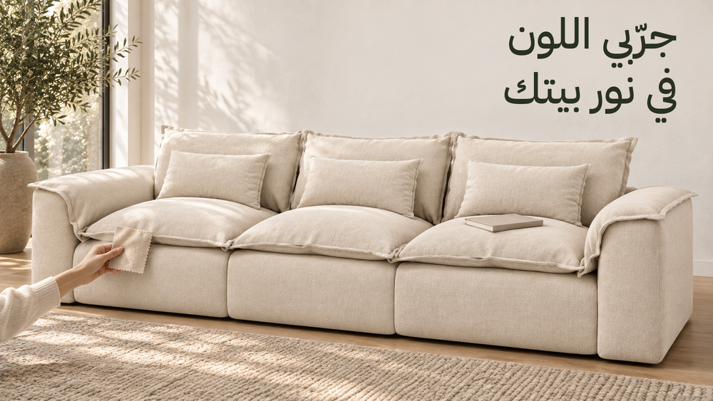كنبة هافن بالقماش الفاتح ظاهرة بالكامل، وإيد بتقارن عينة قماش جنب القعدة في نور نهار، وعنوان جرّبي اللون في نور بيتك